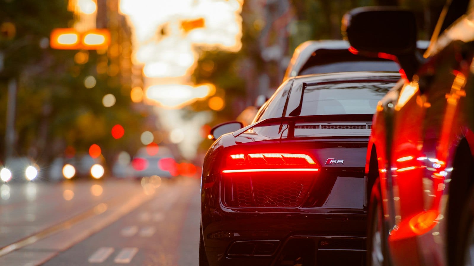 A supercar at dusk on a city street, tail lights lit